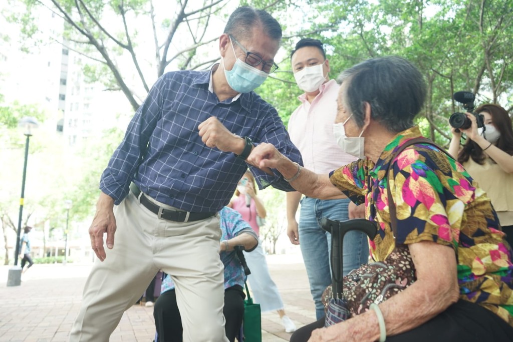 財政司司長陳茂波一行與途人打招呼，並提醒他們記得申請消費券。