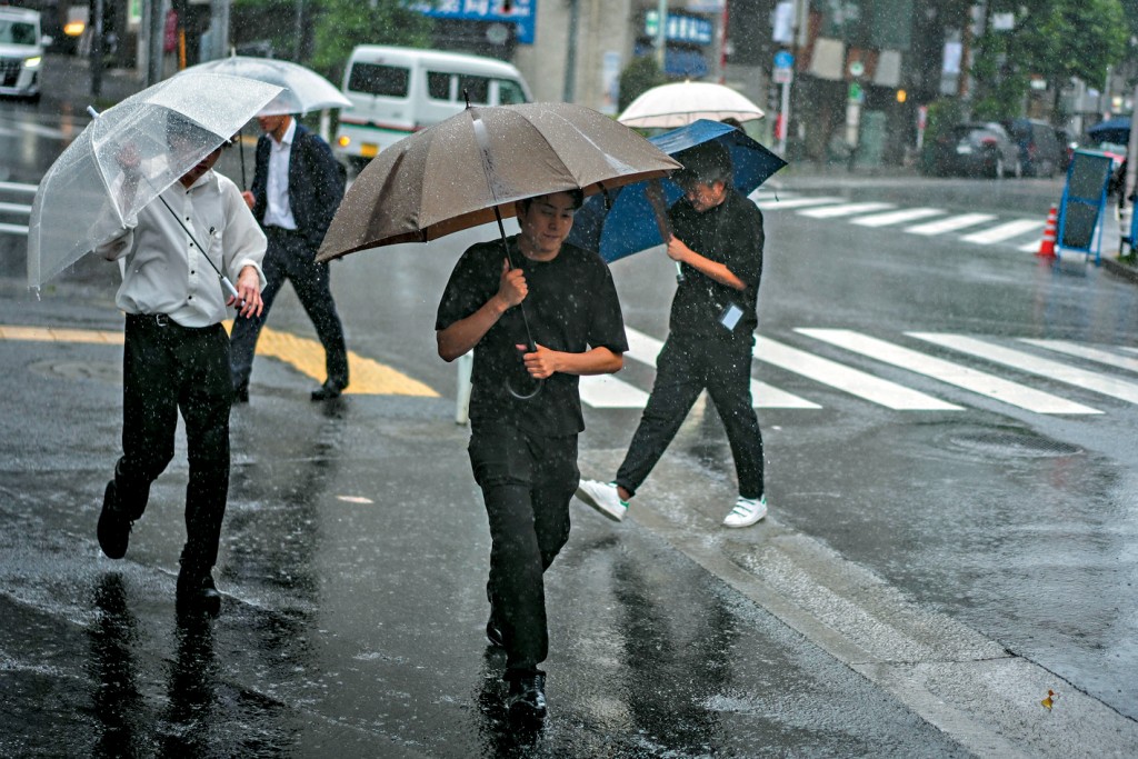 東京行人昨日撐傘在街頭行走。