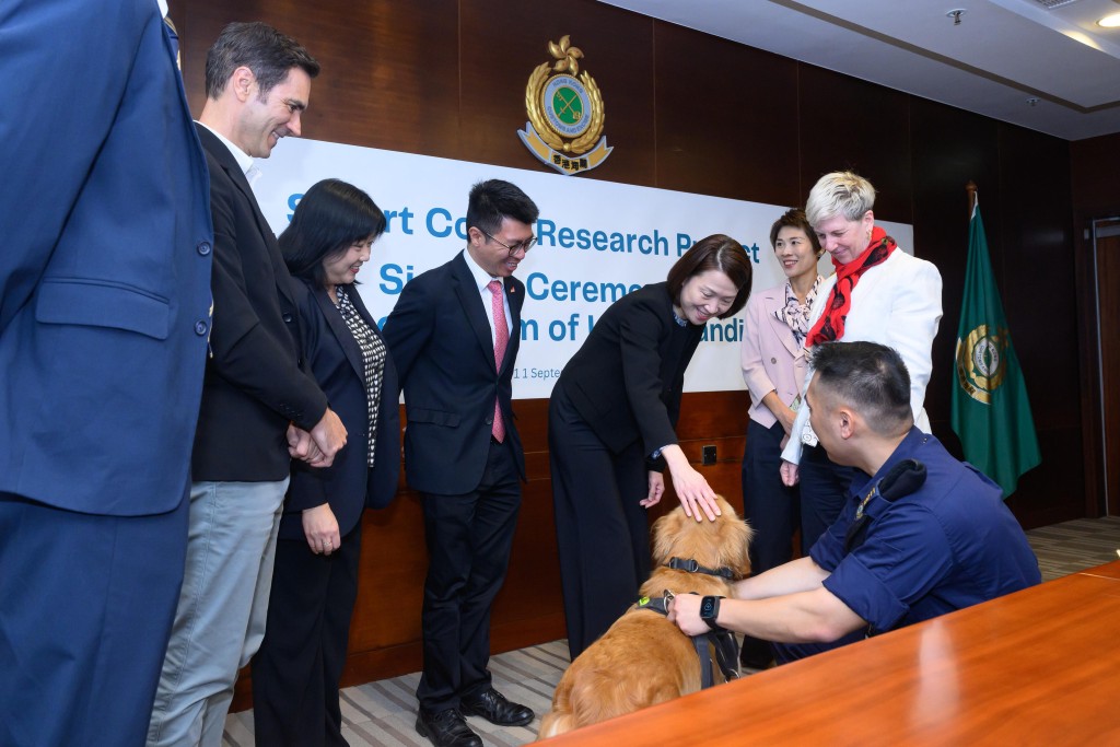 蔣依莉（右四）與其他海關官員和香港城市大學代表於簽署儀式後與搜查犬互動。