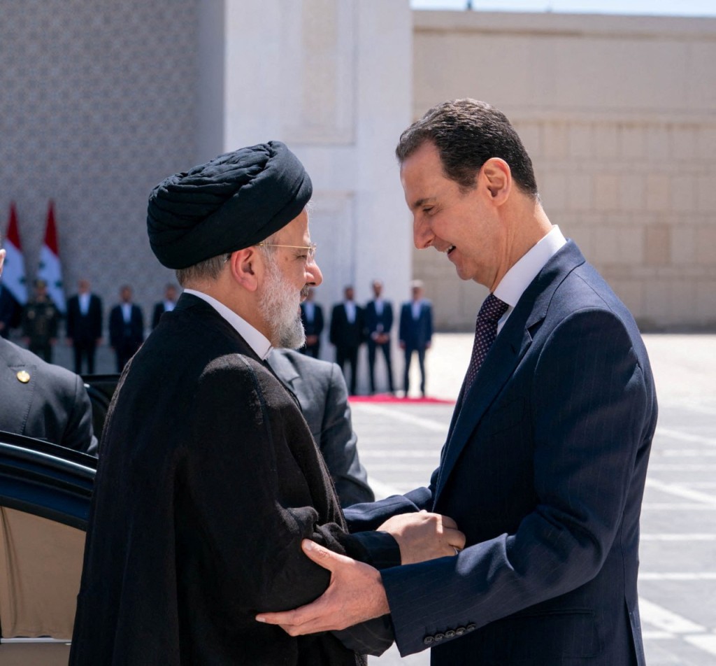 伊朗总统莱希（左）与敍利亚总统阿萨德亲切打招呼。 路透社