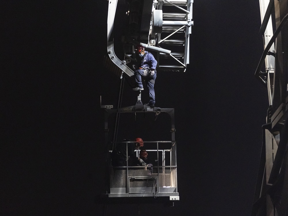 維修技術人員在高空工作，正爬上工程車。