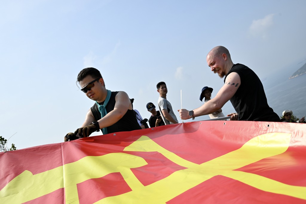 有市民於玉桂山頂上舉起自製的「軍強民樂」旗幟,表示是回應山東艦進港時甲板上的「國安家好」字句。劉駿軒攝 有市民於玉桂山頂上舉起自製的「軍強民樂」旗幟,表示是回應山東艦進港時甲板上的「國安家好」字句。劉駿軒攝