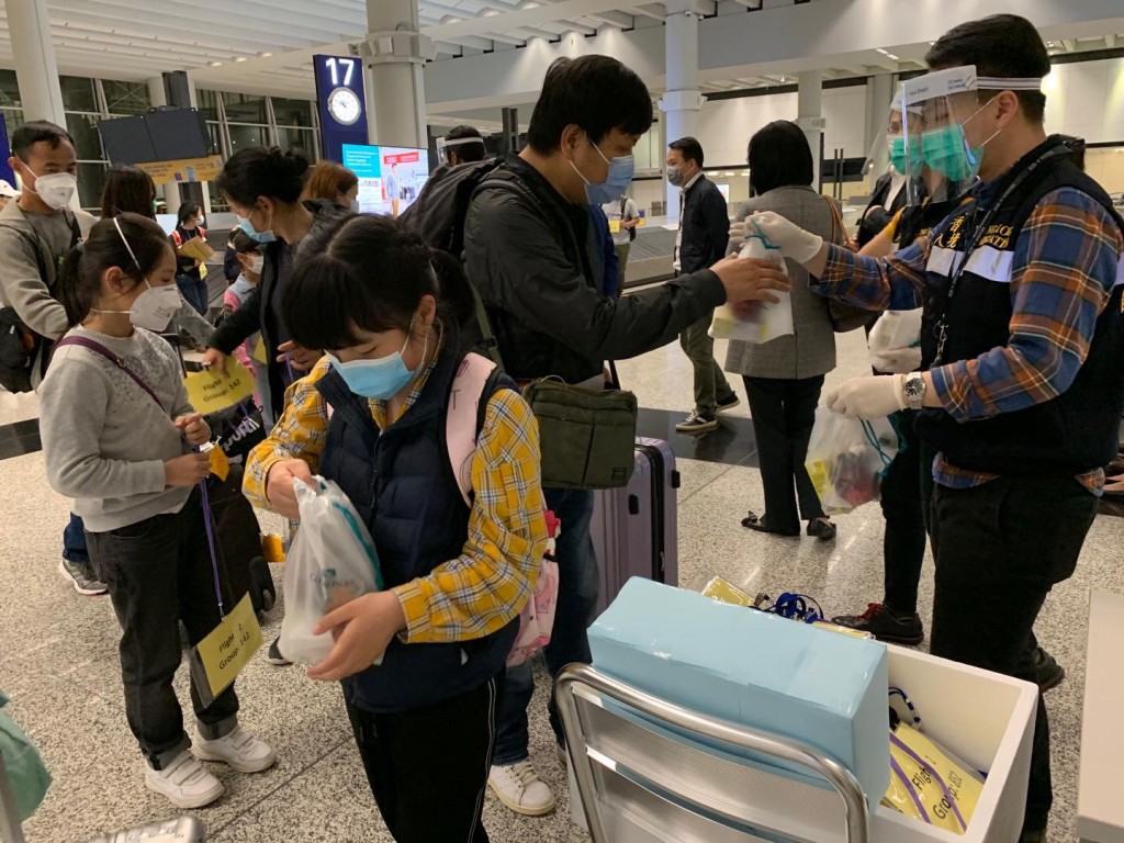 港人到達香港機場後，入境處職員為他們派發由航空公司提供的食物包。讀者提供