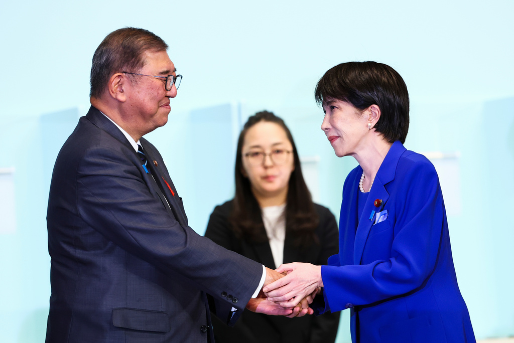 高市早苗與前總裁石破茂握手。美聯社