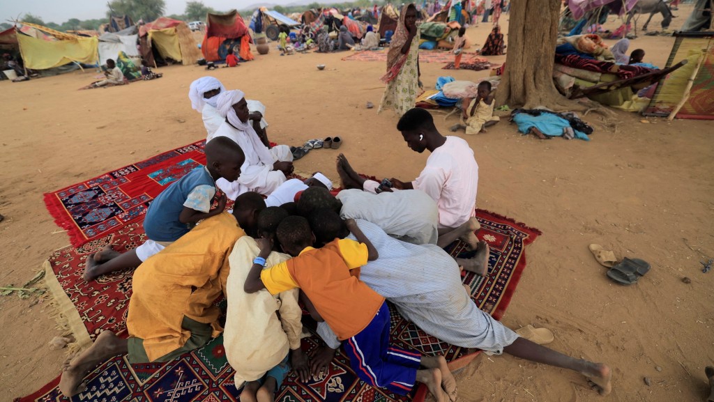 蘇丹孩子們在乍得的臨時避難所圍在一起玩手機。 路透社