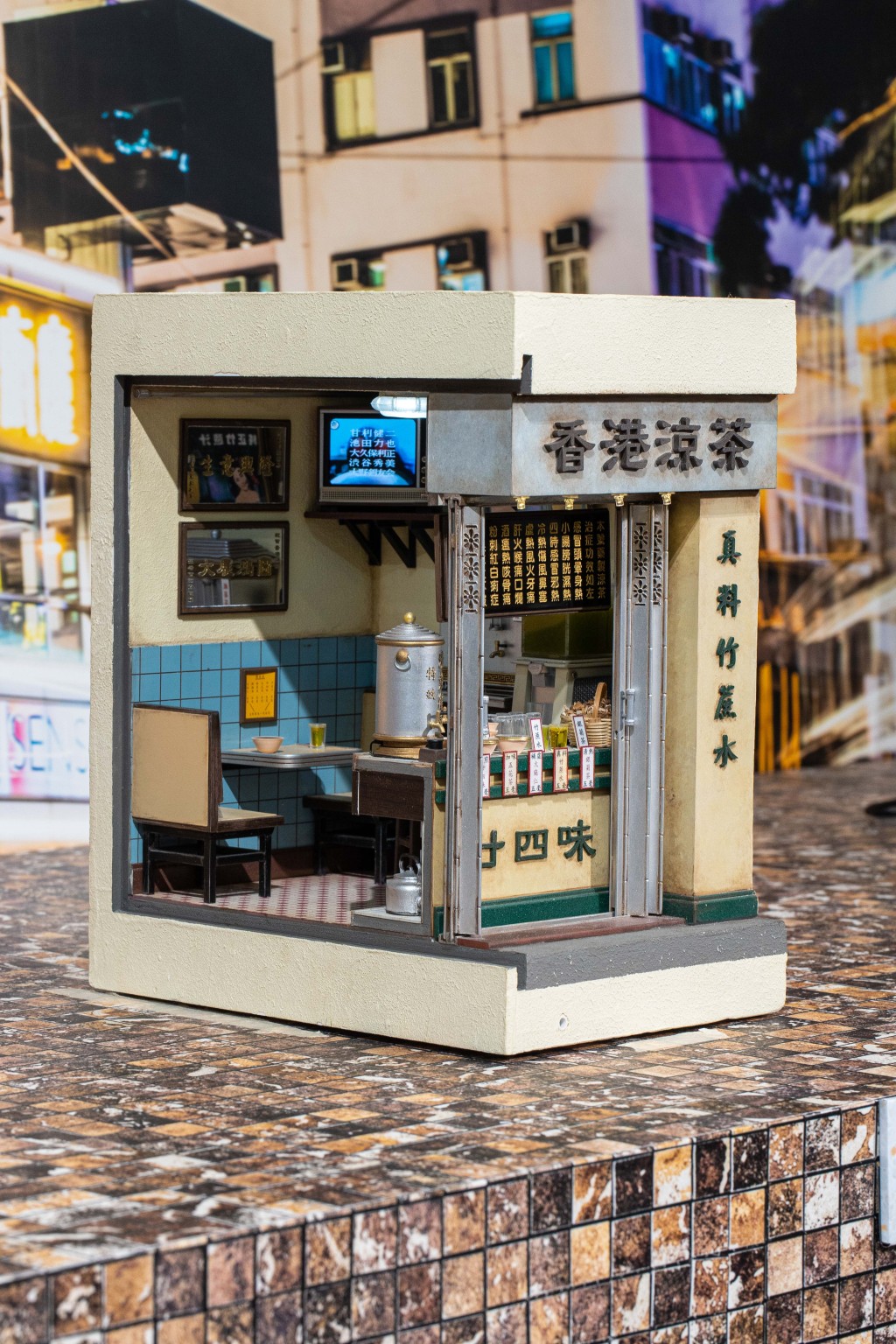 時代變遷，曾經遍布香港街頭巷尾的傳統《涼茶舖》逐漸在鬧市消失。除了舖内常見的「廿四味」、「五花茶」、「銀菊茶」等涼茶，模型還盛載著已被時代淘汰的「大牛龜」電視。