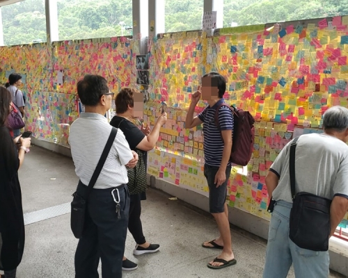 一名黑衣婦人貼上撐警標貼,遮蓋原有標題,引起一名支持反修例男子不滿。讀者提供