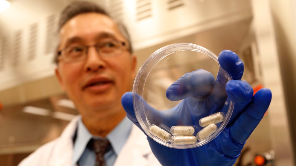 2013年，加拿大卡加里大学的传染病专家Thomas Louie展示研发中的粪菌药丸。 美联社