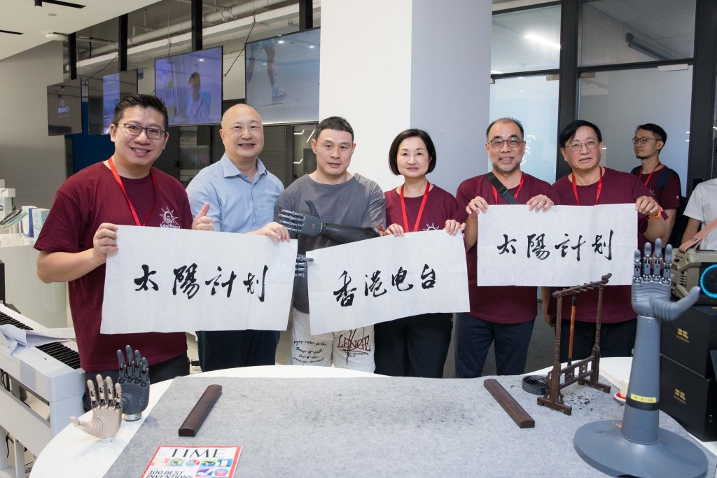 強腦科技體驗─配備智能仿生手的殘疾人士揮毫書法。港台供圖
