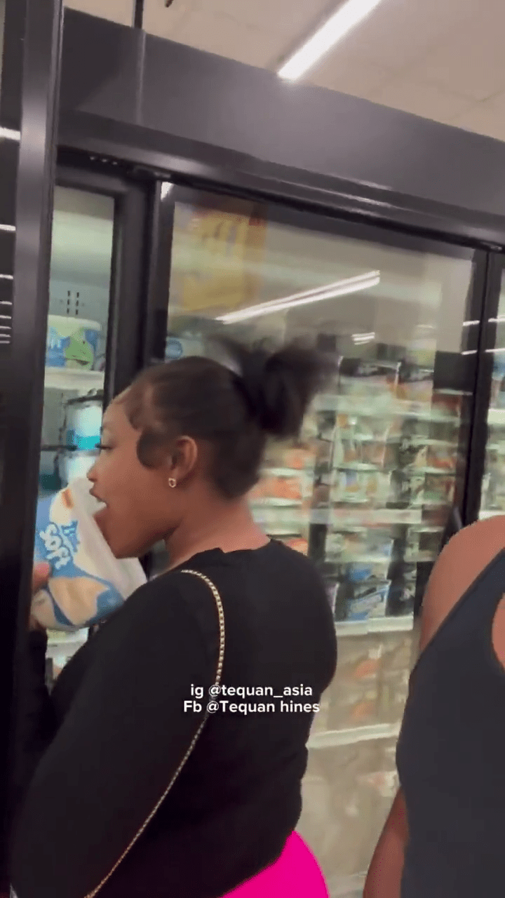 女子舔了一口超市的桶装雪糕。