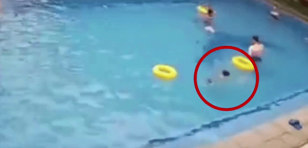 男孩在水中不停掙扎，過程中一位成年男子的游泳圈一度接近該名男孩。