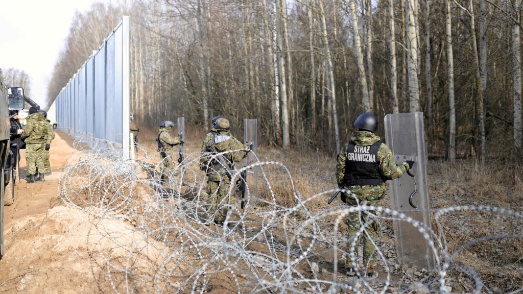 在波兰库兹尼察附近，边防卫队成员和波兰士兵在波白边境的屏障施工现场站岗。 路透社