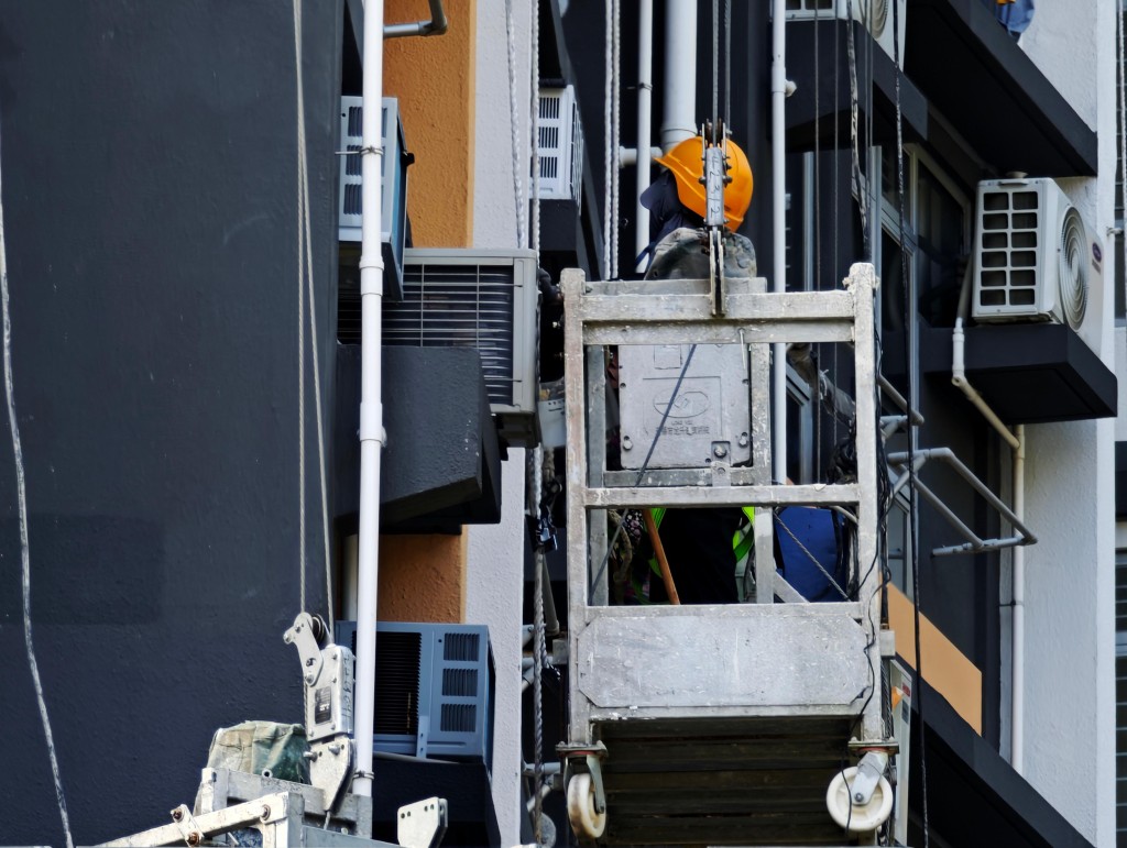 現場有工人正在吊船上進行髹油工程。陳俊豪攝 現場有工人正在吊船上進行髹油工程。陳俊豪攝