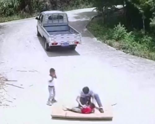 江西男子駕車輾過路上紙皮,後來才發現兩孩子在裡面,自己孩子(紅衣者)更受重傷。影片截圖