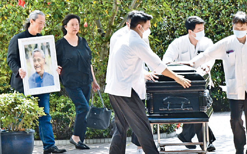 ■吳嘉龍捧着吳耀漢遺照，跟隨靈柩步出教堂。
