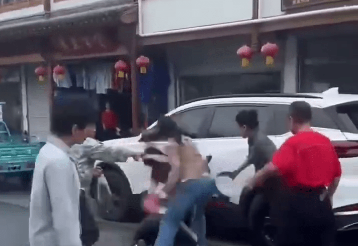 橫間T-恤男被一人推至車旁，其他人則不停施暴。