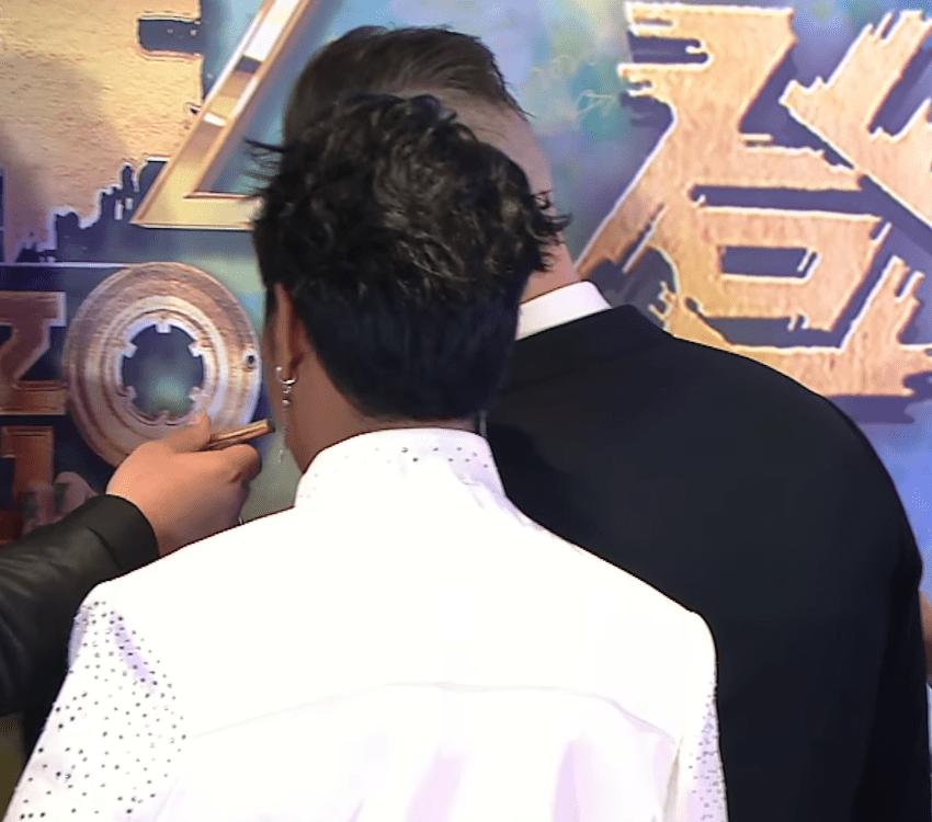 劉洋簽過後將筆遞向李金凱嘴邊。