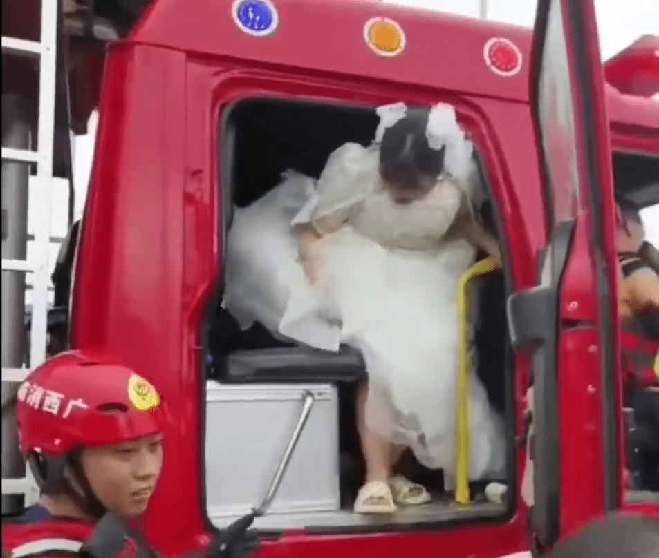 車門打開，新娘在消防員的協助下緩緩下車。