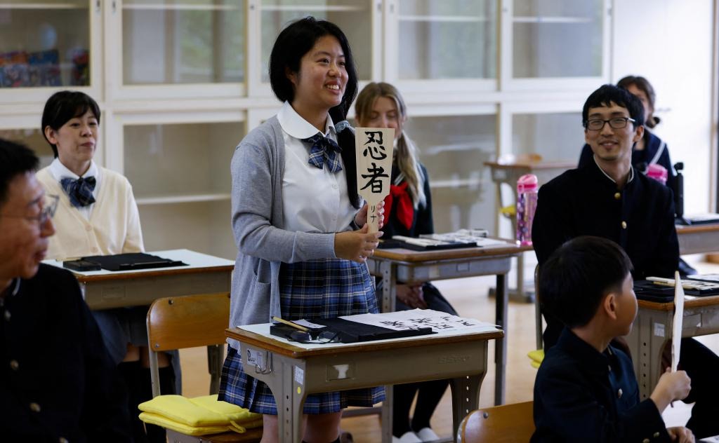 一名美國遊客展示在木板上所寫的毛筆字。 路透社