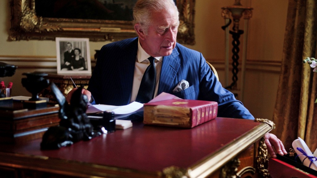 查理斯三世坐在書桌前一隻手按在「紅箱」邊。AP