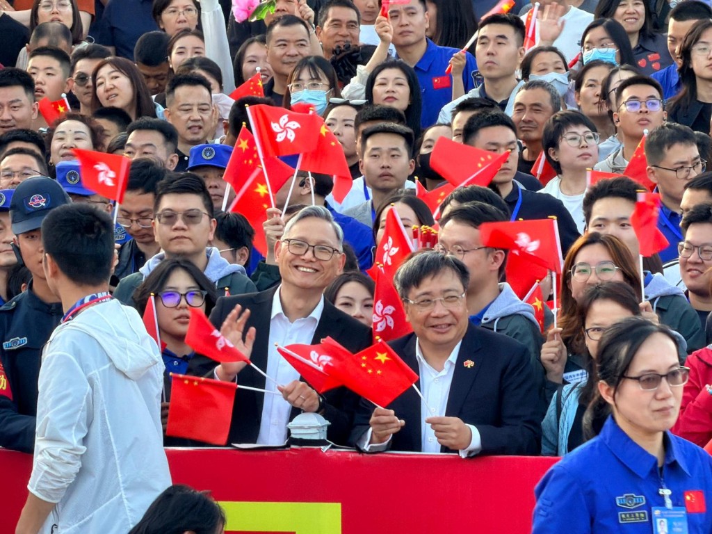 保安局副局長卓孝業(左)、創科署署長李國彬(右)手持國旗及區旗在「頭排」等候航天員出徑。郭詠欣攝 保安局副局長卓孝業(左)、創科署署長李國彬(右)手持國旗及區旗在「頭排」等候航天員出徑。郭詠欣攝