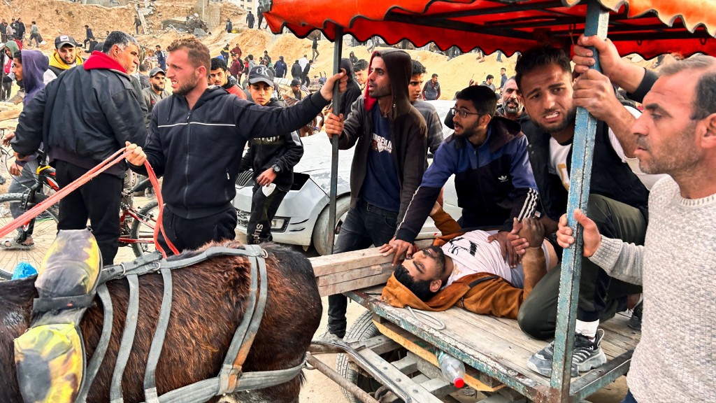 巴勒斯坦人用驢車帶着受傷的同伴去等候派發麵粉。 路透社
