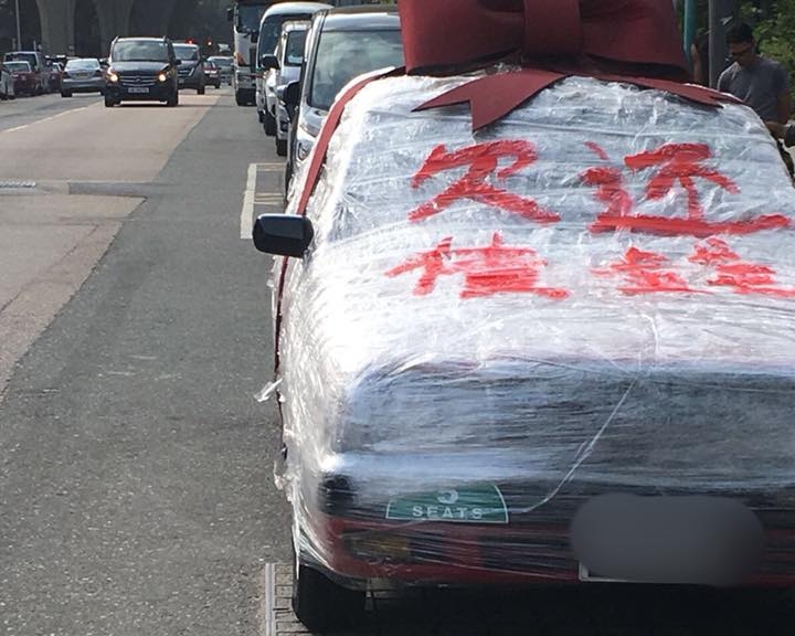 「被包膠」的的士上面寫上「欠債還錢」外，還有一個大蝴蝶結，猶如一份超級大禮物般。我的你的紅的fb專頁