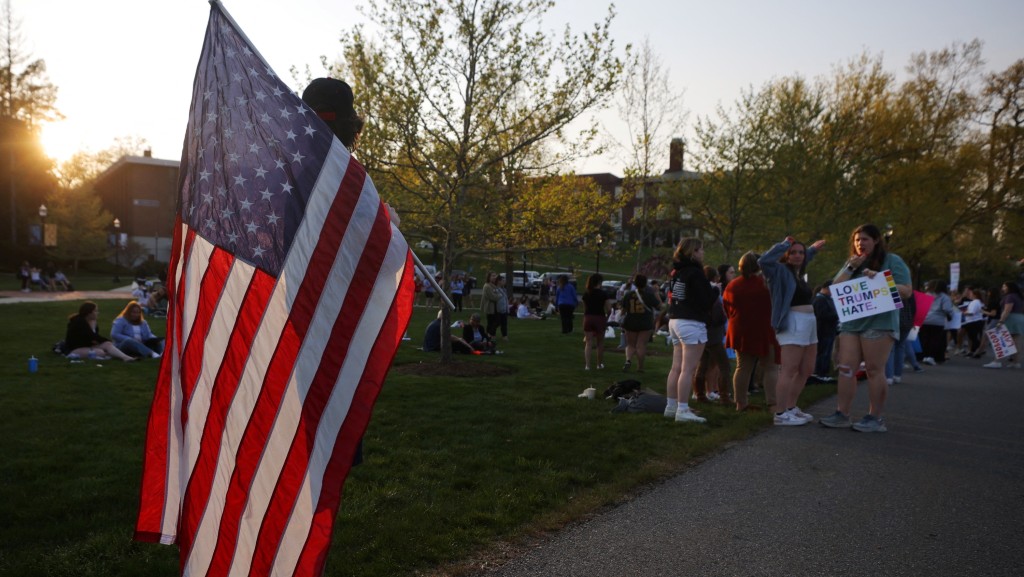 一名特朗普支持者持美国国旗走近抗议人群。 路透社