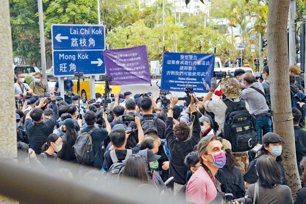 警方向法院大楼外人群高举蓝旗、紫旗，警告非法集结及违反国安法。