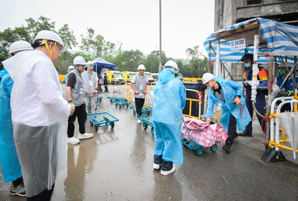 卓永興(左)觀看民安隊隊員和動員公務員聯同地區服務及關愛隊伍義工,協助居民搬運物品。 卓永興(左)觀看民安隊隊員和動員公務員聯同地區服務及關愛隊伍義工,協助居民搬運物品。