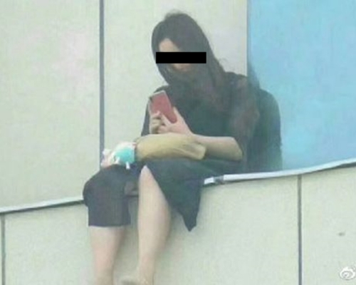 李女危坐在一棟25層高樓的8樓外。網圖