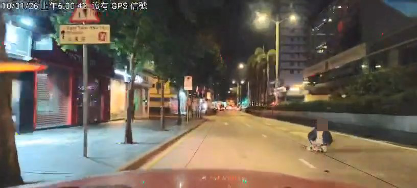 一名身穿藍色外套的外籍女子坐在美麗都大廈對開的彌敦道。網上片段截圖