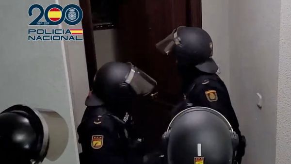 警方撬門突襲可疑公寓。 Policía Nacional