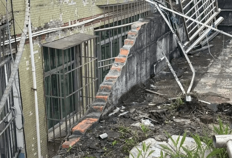 水箱撞穿天台近6米長的圍牆，繼而從兩棟樓宇之間直墮地面。 南方都市報