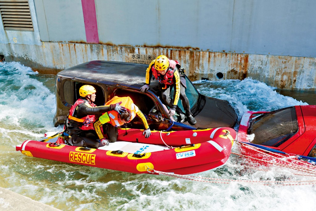 消防拯救隊成員演練如何在車子掉進水裏的情況下，救出被困車內的人。
