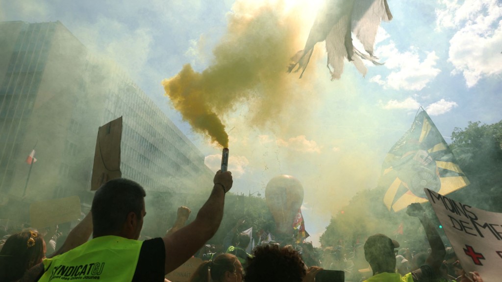 黃背心聯盟成員手持煙霧彈參加國際勞動節遊行集會。 法新社