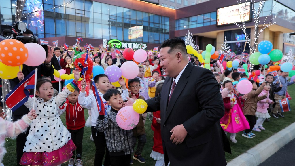 金正恩在平壤和盛新區第三期萬套住宅建設項目落成典禮與小朋友互動。 路透社