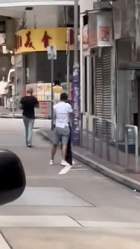 一名身穿白色Tee的男子與一名長髮女子在尖沙咀街頭拉扯糾纏。