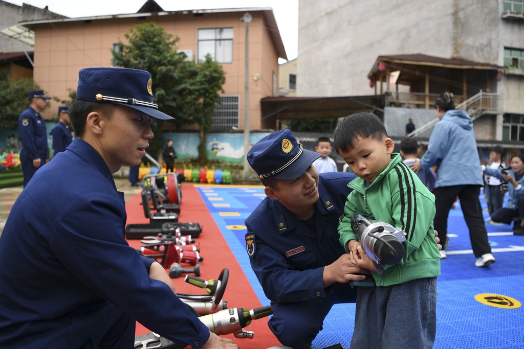 贵州省遵义市余庆县白泥镇下里幼稚园学生体验使用消防救援器材。新华社