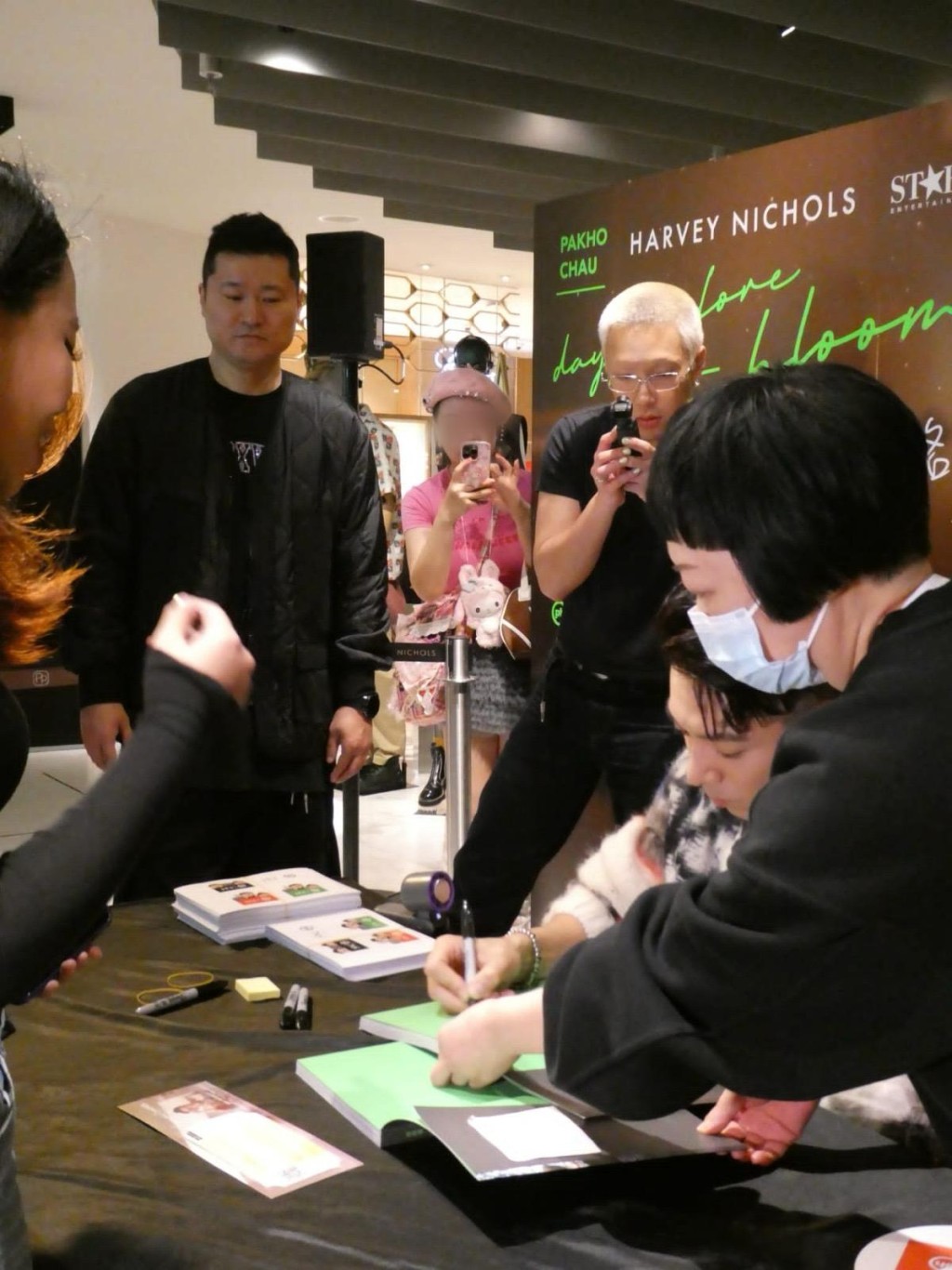 粉红衫女子未有激烈行为，在围栏外以手机拍摄柏豪为粉丝签书情况。