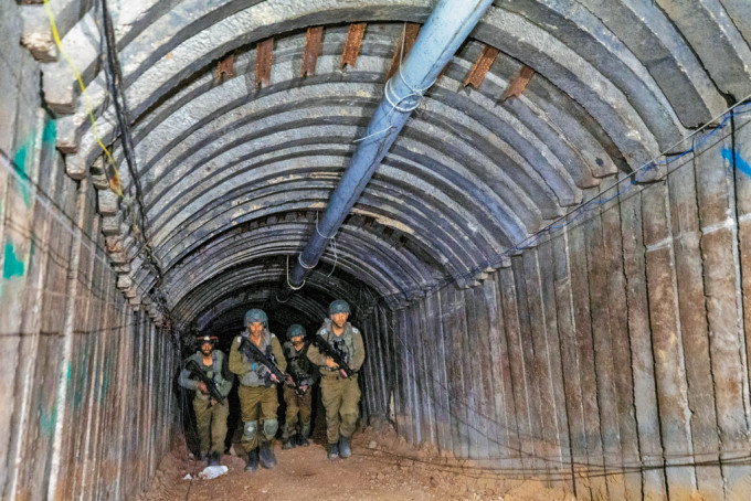 以军在加沙北部埃雷兹口岸附近发现的大型地道内巡视。