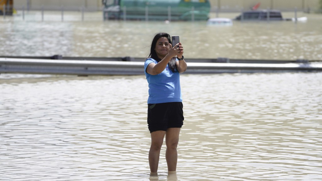 杜拜罕見暴雨，水淹街道，女子在水中央拍下這難得一見的奇景。 美聯社