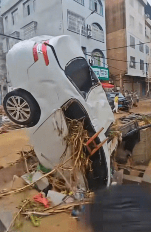 白色轎車倒立在坑渠邊。新京報