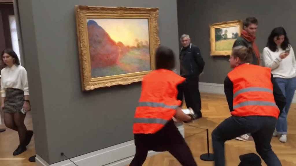 兩名身穿橙色背心的環保示威者，拿薯蓉向畫作潑灑。