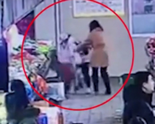 陌生婦人突然抱起女童，將其頭部撞向菜攤。 網上圖片