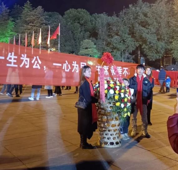 有人手捧鮮花帶領紀念隊伍駐足瞻仰毛主席銅像。