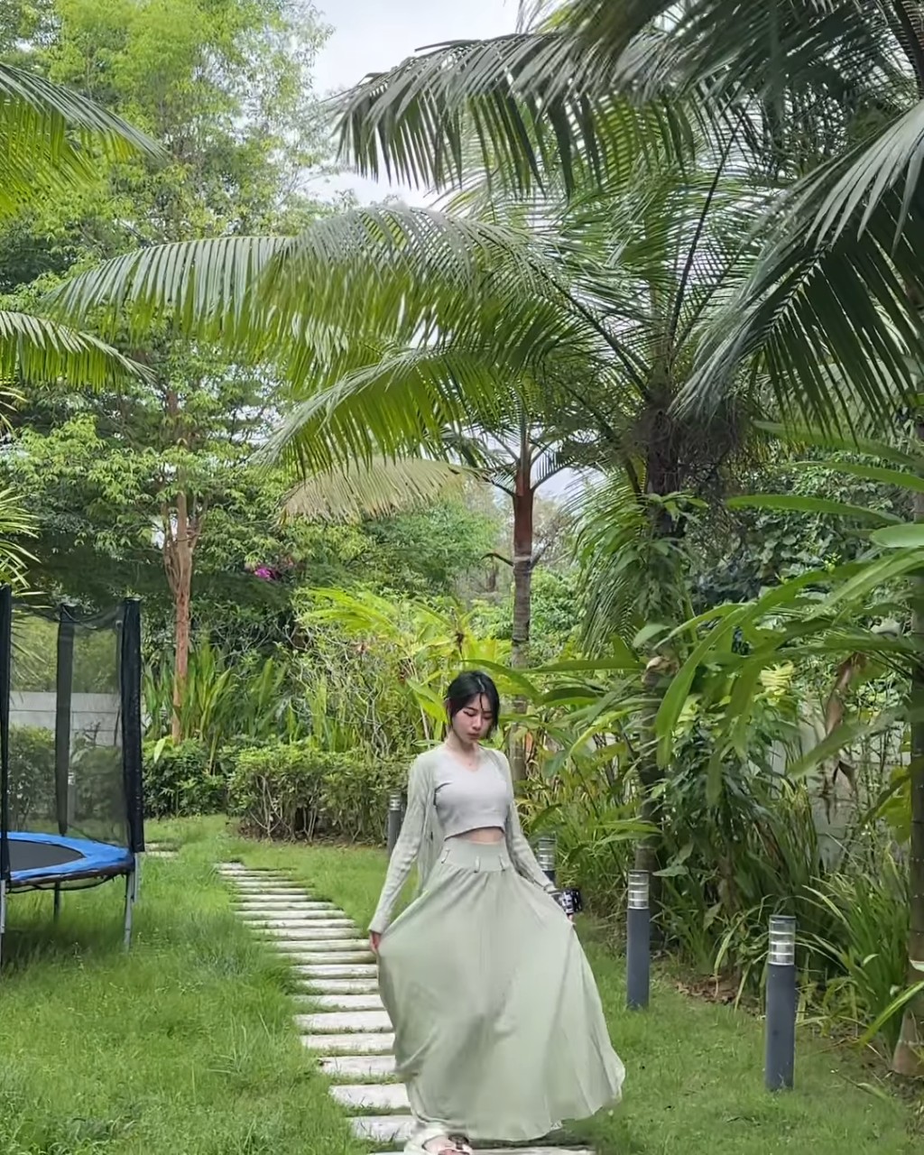 穿上淺綠色長裙的林明禎於花園內的石春路行Catwalk。