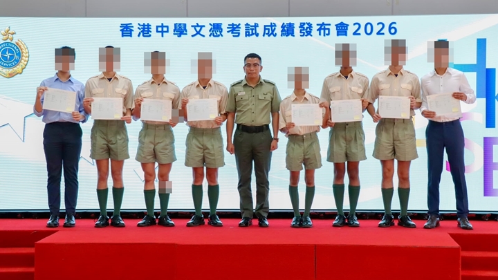 懲教署沙咀懲教所監督潘浩霖（中）向應屆考生頒發文憑試成績通知書。麥鍵瀧攝