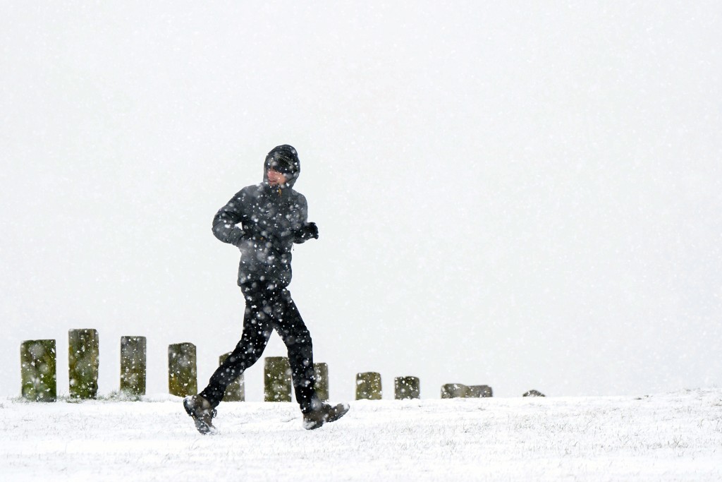 一名男子在贝德福德郡 Dunstable Downs 的雪地里奔跑。AP