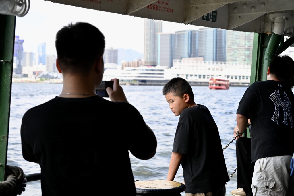 不少旅客舉起手機拍攝維港兩岸景色。